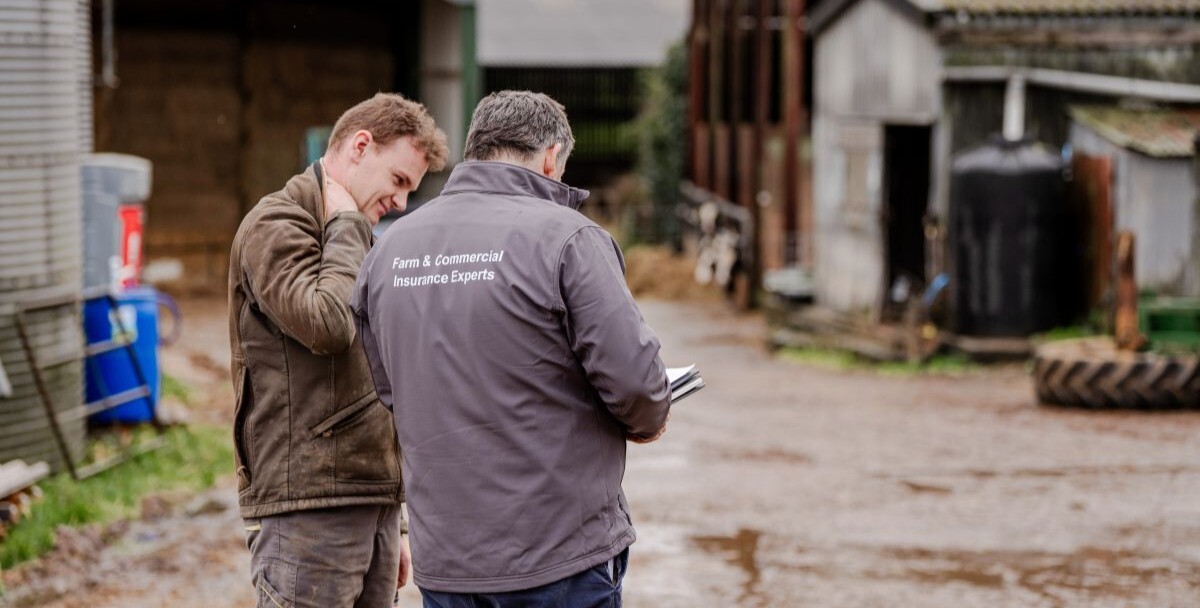 Farm advisor discussing paperwork with farmer in farmyard